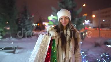 画像中幸福的女人在城市购物后在圣诞节装饰的街道上，慢镜头。 美女美女